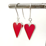 Red heart-shaped earrings with silver hooks on a white background