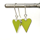 Heart-shaped earrings with green and silver colors hanging on a white background.